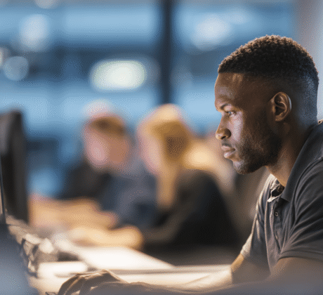 Ein Mann sitzt konzentriert vor seinem Computer in einem modernen Büro und bearbeitet seine E-Mails
