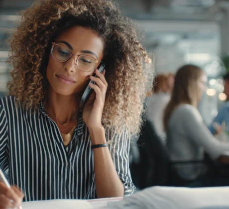 Eine Sekretärin sitzt in einem modernen Büro an ihrem Schreibtisch, telefoniert, schreibt E-Mails und organisiert Termine am Computer.