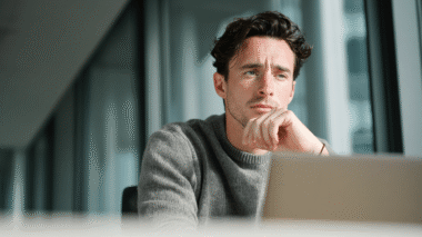 Mann arbeitet in einem Büro und schaut konzentriert auf seinen Computer