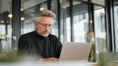 Mann sitzt vor einem Laptop im Büro und arbeitet