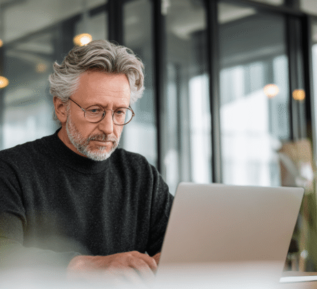 Mann sitzt vor einem Laptop im Büro und arbeitet