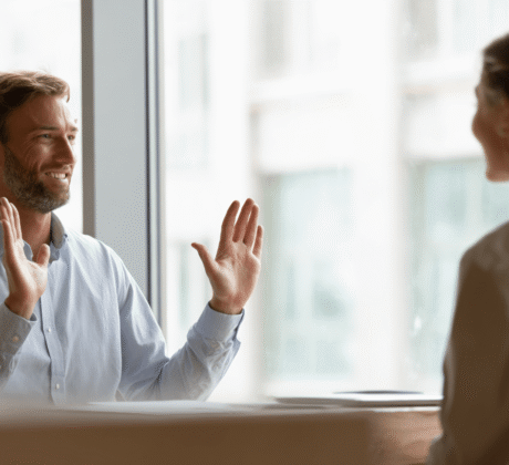 Mann sitzt im Büro einer Frau gegenüber und gestikuliert mit seinen Händen, dass er das Angebot ablehnt