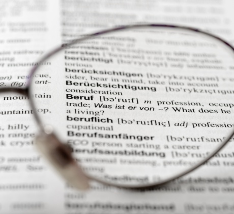 Ein offenes Wörterbuch mit dem Zoom auf eine Brillenglas.