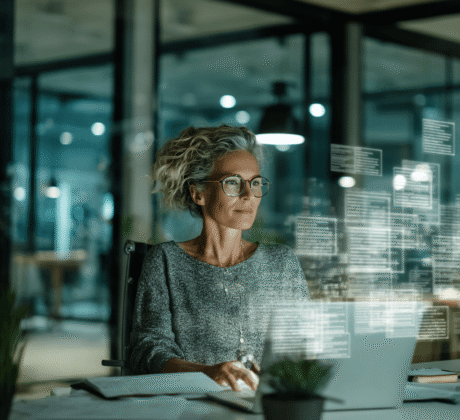 Frau Ende 40 arbeitet am Laptop, über dem ein Hologramm von Dokumenten schwebt – Symbol für Word-Dateien und digitale Dokumente im Büro.