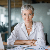 CFO, elegante Frau Ende 40 mit kurzen Haaren und Perlenkette im modernen Büro, arbeitet an Finanzen und Buchhaltung.