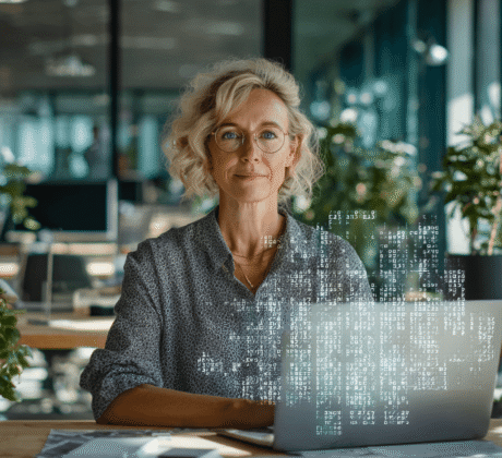 Frau Ende 40 arbeitet am Laptop, über dem ein Hologramm mit Zahlen und Tabellen schwebt – Symbol für Excel und Datenanalyse
