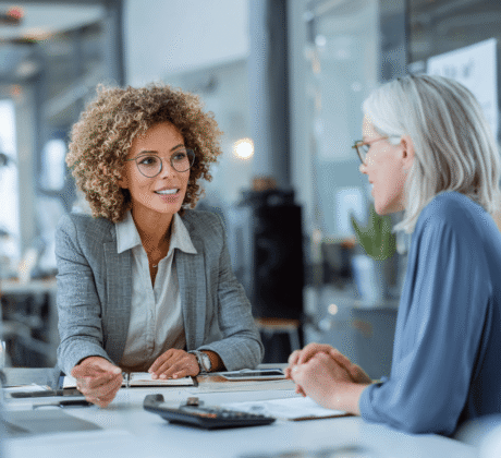 Zwei Business-Professionals am Bürotisch mit Geldscheinen und Taschenrechner – Symbol für Geld verhandeln, Gehaltsgespräch und Finanzverhandlung.
