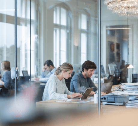 Mitarbeitende arbeiten im modernen Büro digital mit Laptops und Scanner – Symbol für Digitalisierung und papierloses Arbeiten.