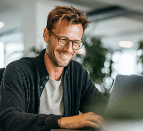 Mann im Büro tippt E-Mail am Laptop und achtet auf korrekte Anreden in der geschäftlichen Korrespondenz.