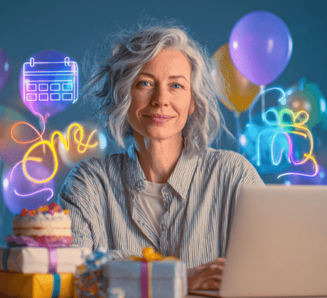 Frau Ende 40 mit weißen Strähnen arbeitet am Laptop, über dem ein holografischer Kalender mit Ballons, Geschenken und Torte schwebt.