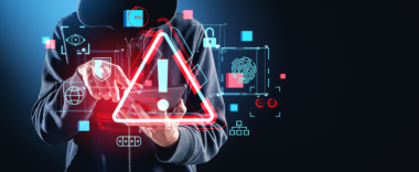 Person im dunklen Hoodie. Davor ein Hologram mit einem Vorsicht-Zeichen sowie Icons, die auf Sicherheit verweisen.