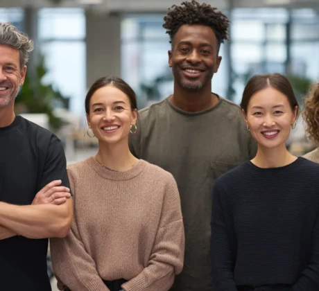 Eine Gruppe diverser Arbeitskollegen schaut lächelnd in die Kamera.