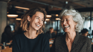 Zwei Kolleginnen lachen gemeinsam, Symbolfür Humor im Büro gegen Stress