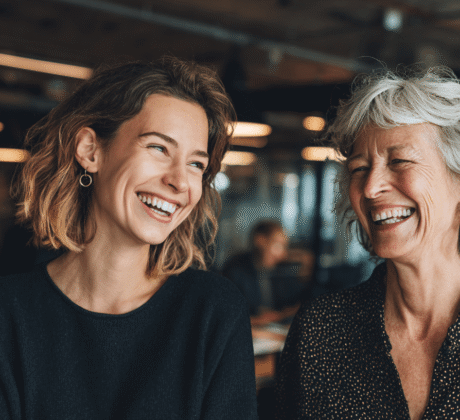 Zwei Kolleginnen lachen gemeinsam, Symbolfür Humor im Büro gegen Stress
