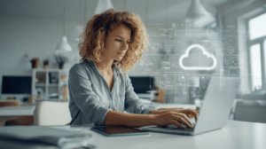 Junge Büromitarbeiterin mit dunkelblonden Locken am Laptop, über ihr ein Wolken-Hologram. Symbolbild für papierloses Büro