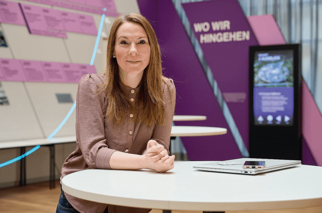 Isabell Ott steht am Stehpult und schaut in die Kamera.