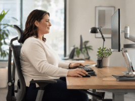 Assistentin von der Seite zu sehen auf ergonomischem Stuhl im Office