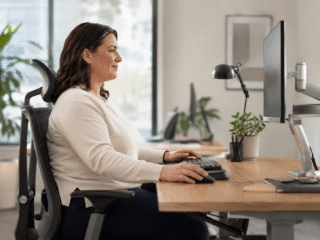 Assistentin von der Seite zu sehen auf ergonomischem Stuhl im Office