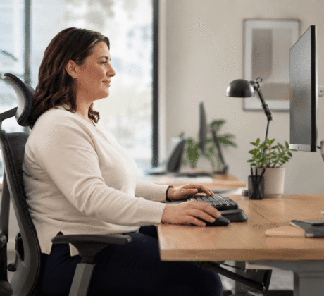 Assistentin von der Seite zu sehen auf ergonomischem Stuhl im Office